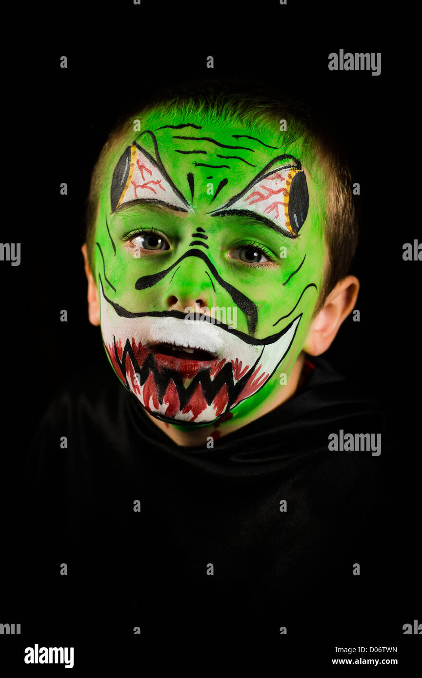 Ein kleiner Junge mit seinem Gesicht in Halloween Thema Stil Horror UK grün lackiert Stockfoto