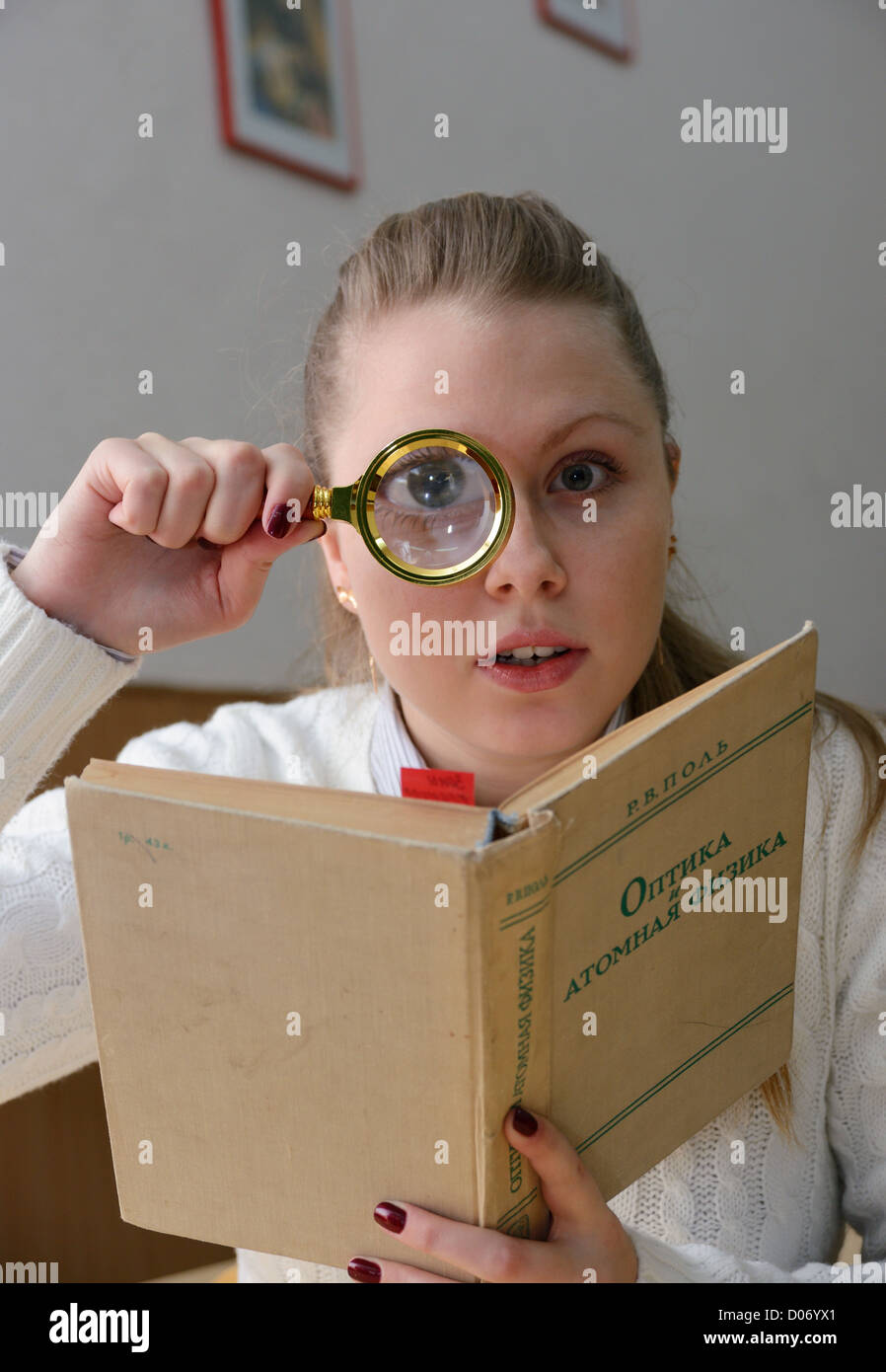 Frau liest ein Buch mit einer Lupe Stockfoto