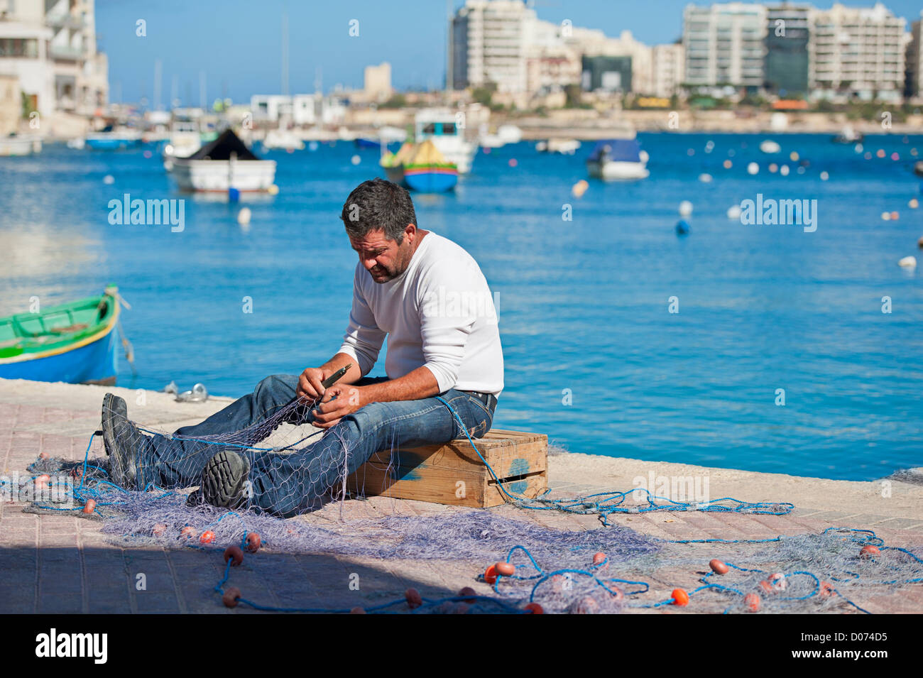 Maltesische Fischer seine Netze reparieren Stockfoto