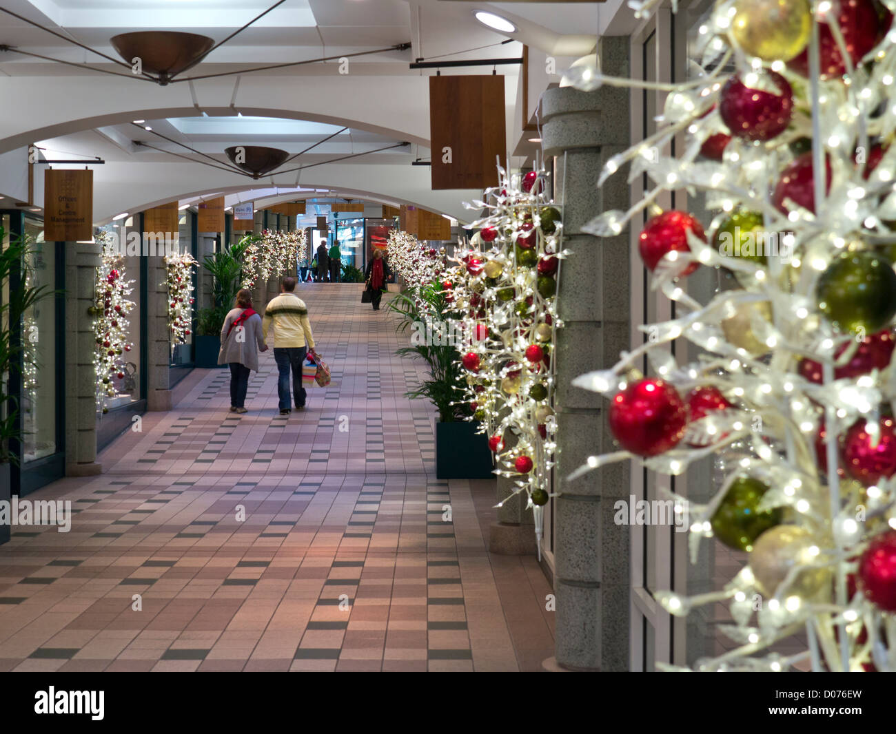 Traditionellen Weihnachtsschmuck mit jungen Paar Einkaufstaschen tragen, in einer ruhigen Tunsgate Shopping Mall Guildford UK Stockfoto