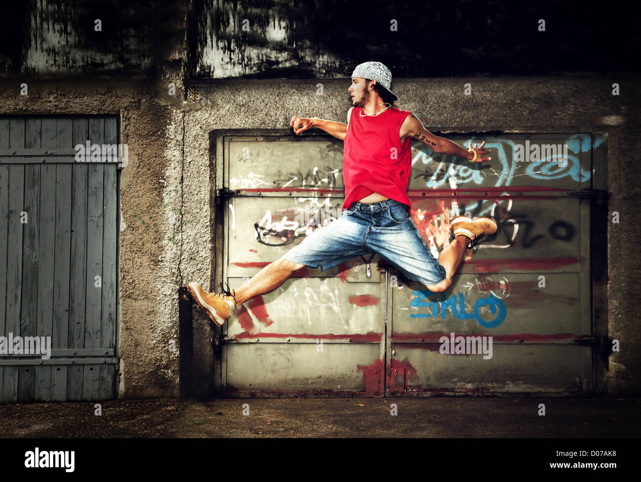 Junger Mann springen / Tanz auf Grunge-Graffiti-Wand-Hintergrund Stockfoto