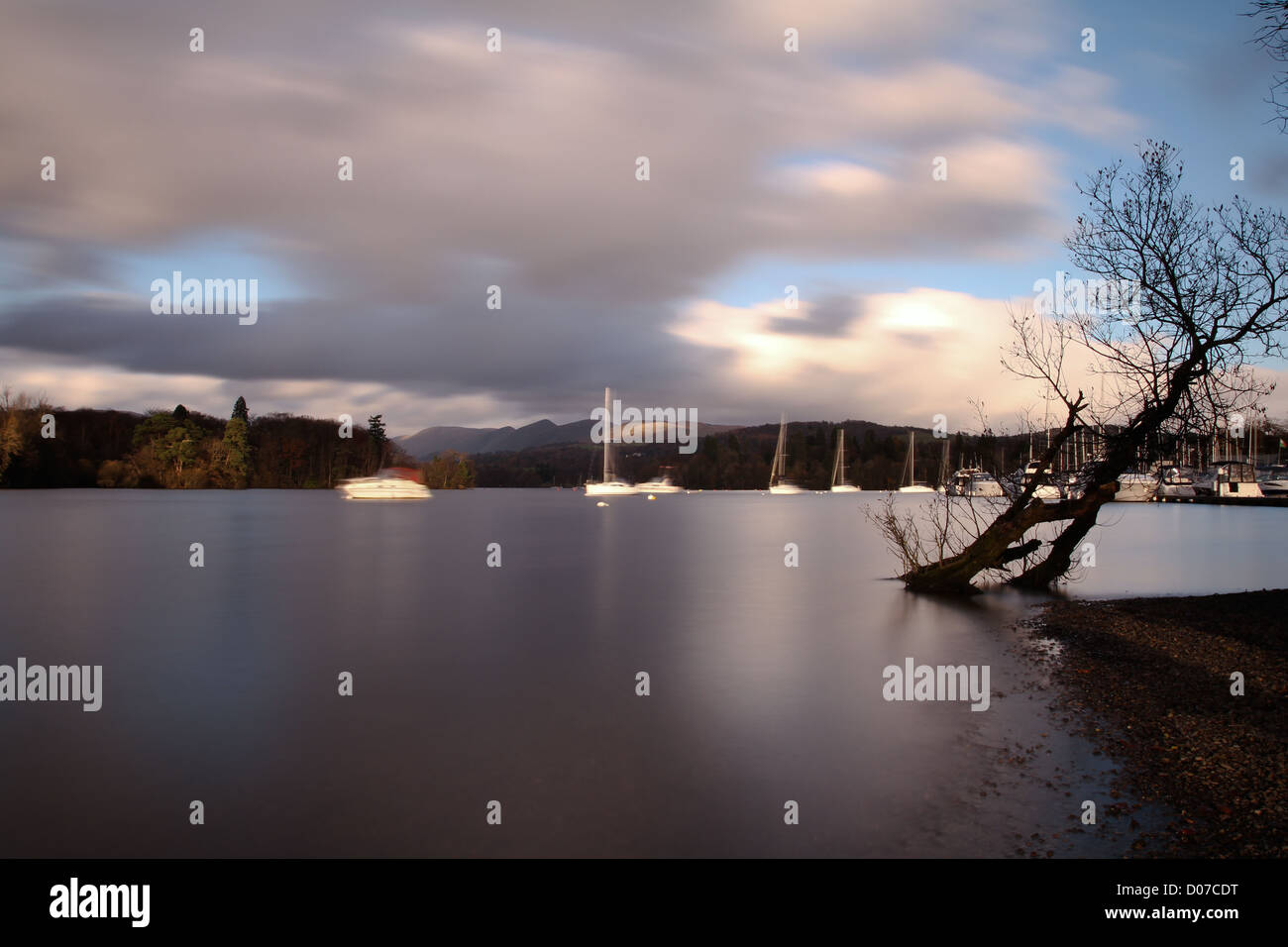 Langzeitbelichtung der Boote am Lake Windermere mit Baum im Vordergrund Stockfoto