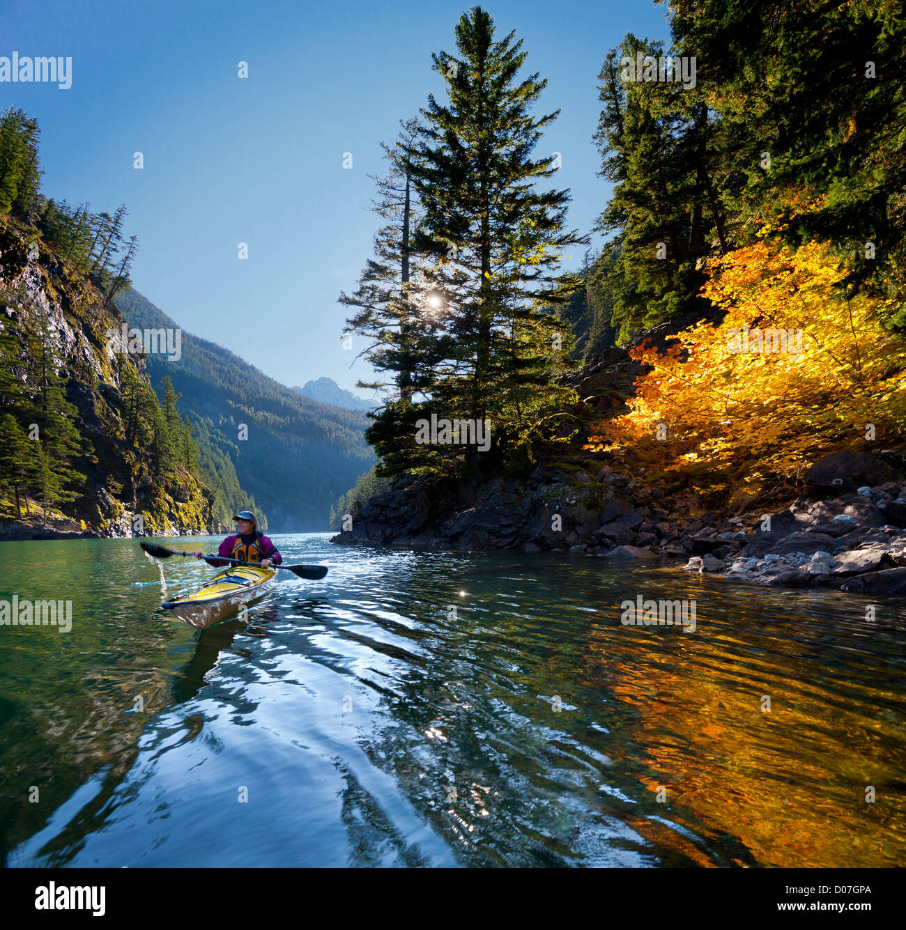 USA, Washington State, North Cascades National Park. Frau Kajakfahrer Meer am See Diablo mit Birke und Rebe Ahorn. (MR) Stockfoto