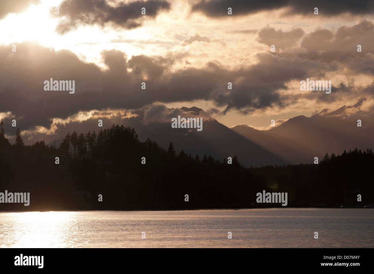 USA, WA, Bainbridge Island. Untergehende Sonne bricht Wolken. Blick vom Bainbridge Island in Richtung Kitsap Peninsula, Olympic Mountains. Stockfoto