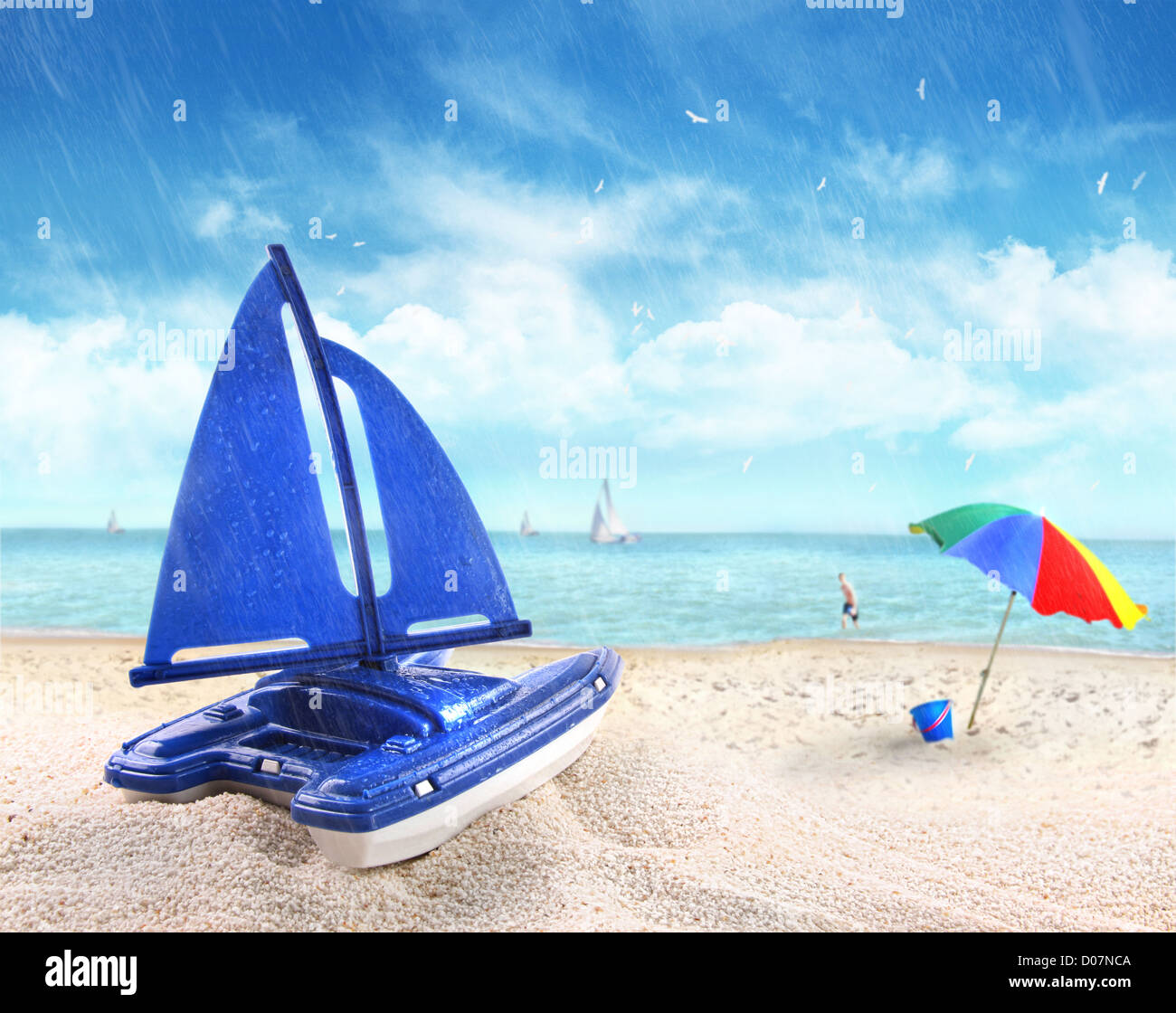 Spielzeug-Segelboot in Sand mit Strand-Szene im Hintergrund Stockfoto