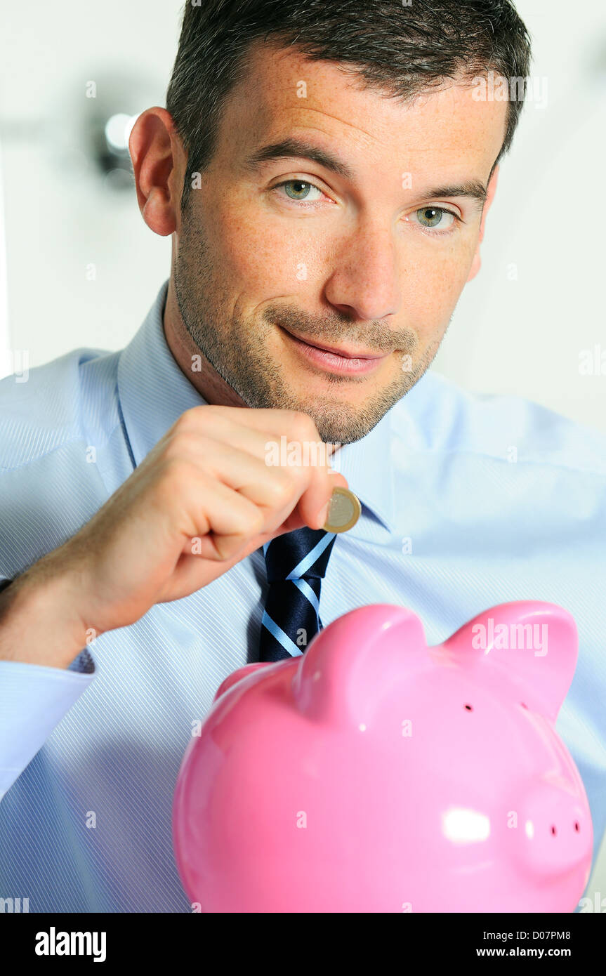 Geschäftsmann, die Matten einer Münze in die Schweinchen-förmigen rosa Schwein Stockfoto