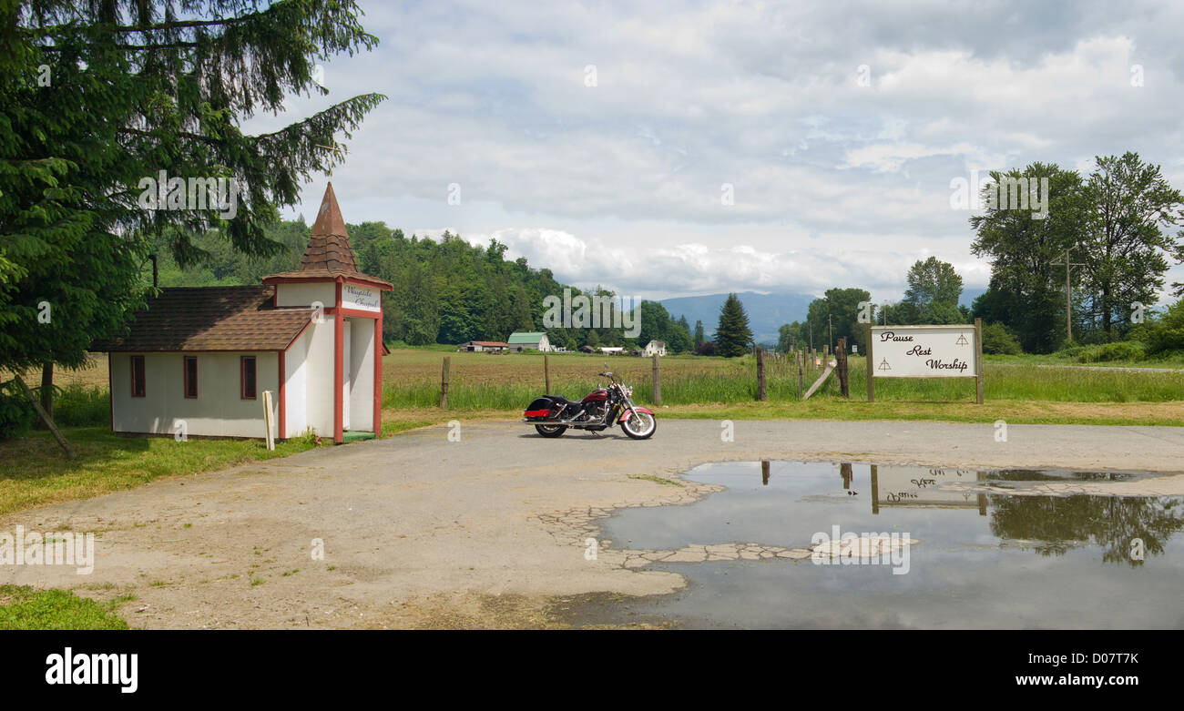 Ein Motorrad geparkt ist durch eine kleine Kirche am Straßenrand Heiligtum im östlichen Washington State, USA. Stockfoto