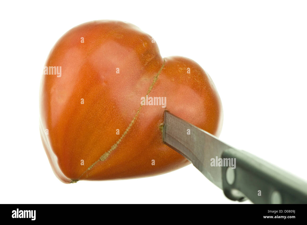 herzförmige Tomaten durchbohrt von Messer auf reinen weißen Hintergrund Stockfoto