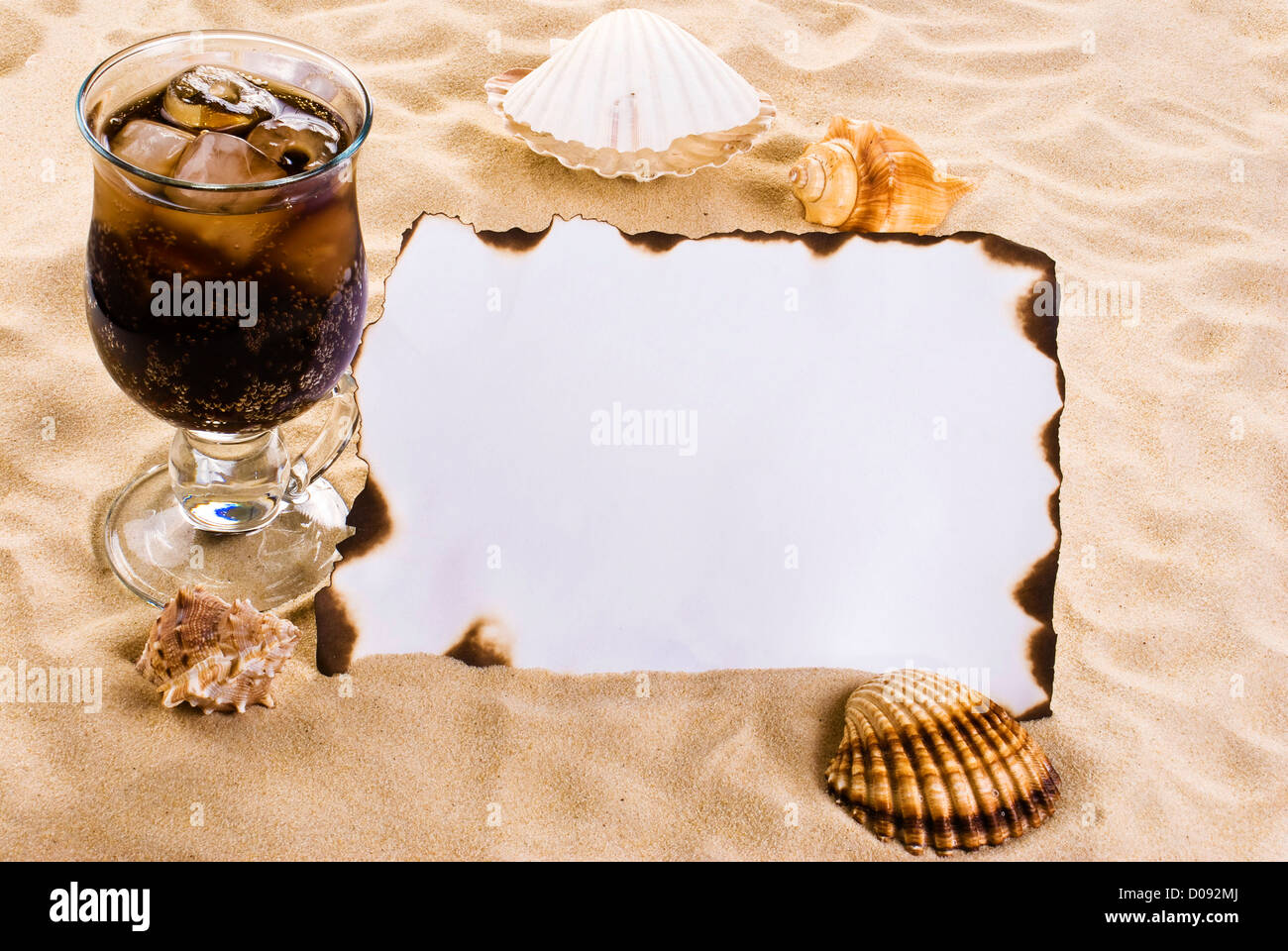 Verbrannten Papier auf dem Sand mit Muscheln und Eis Kaltgetränk Stockfoto