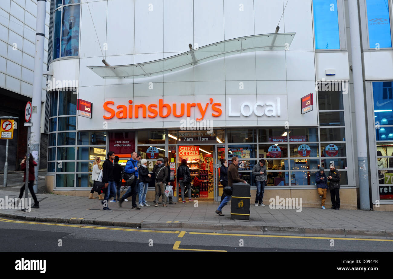 Shopper, vorbei an kleinen Supermarkt ein Sainsbury in North Street Brighton UK Stockfoto