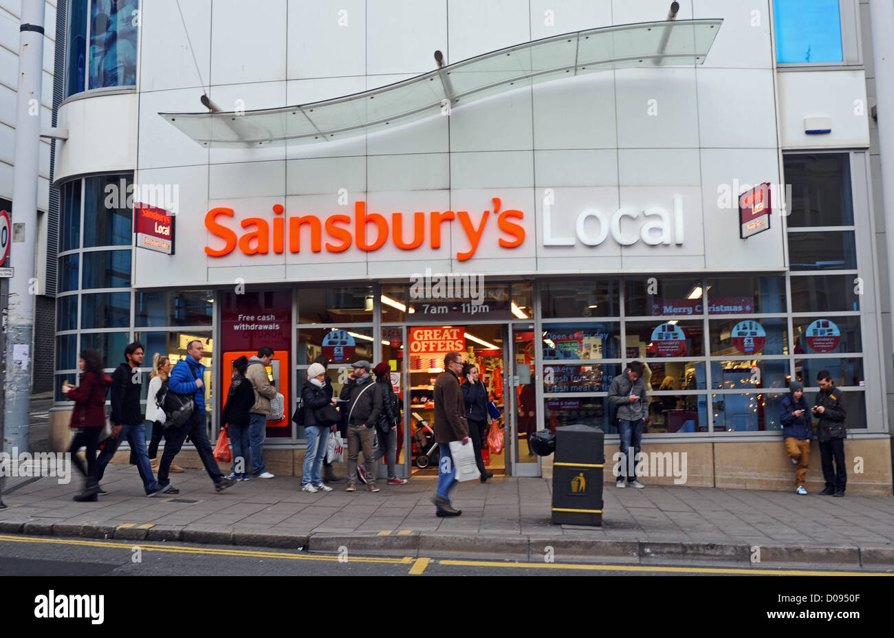Shopper, vorbei an kleinen Supermarkt ein Sainsbury in North Street Brighton UK Stockfoto