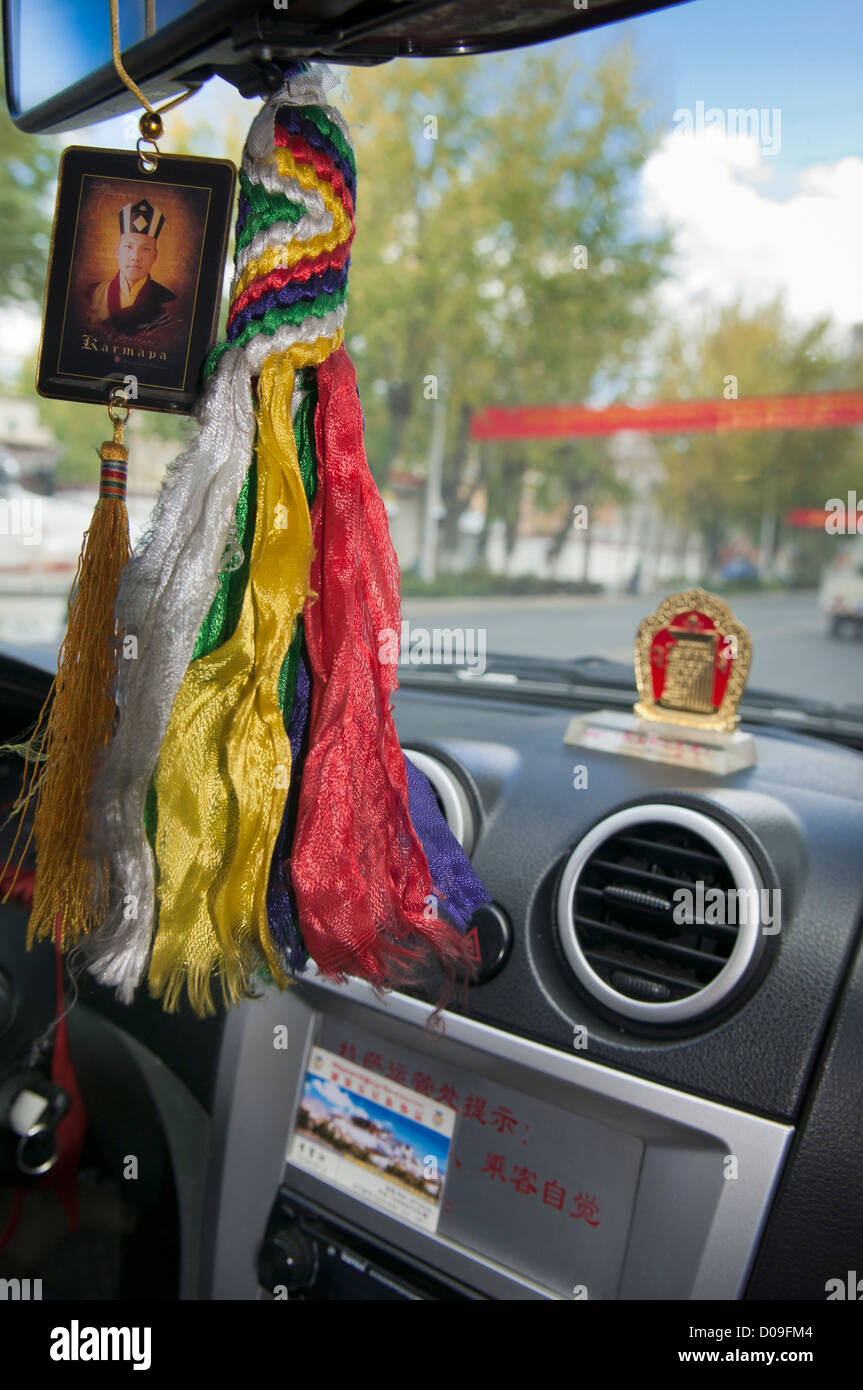 Bild der Mönch hängt von Taxi Driver-Spiegel während religiöse Andenken auf Armaturenbrett, Lhasa, Tibet sitzt Stockfoto