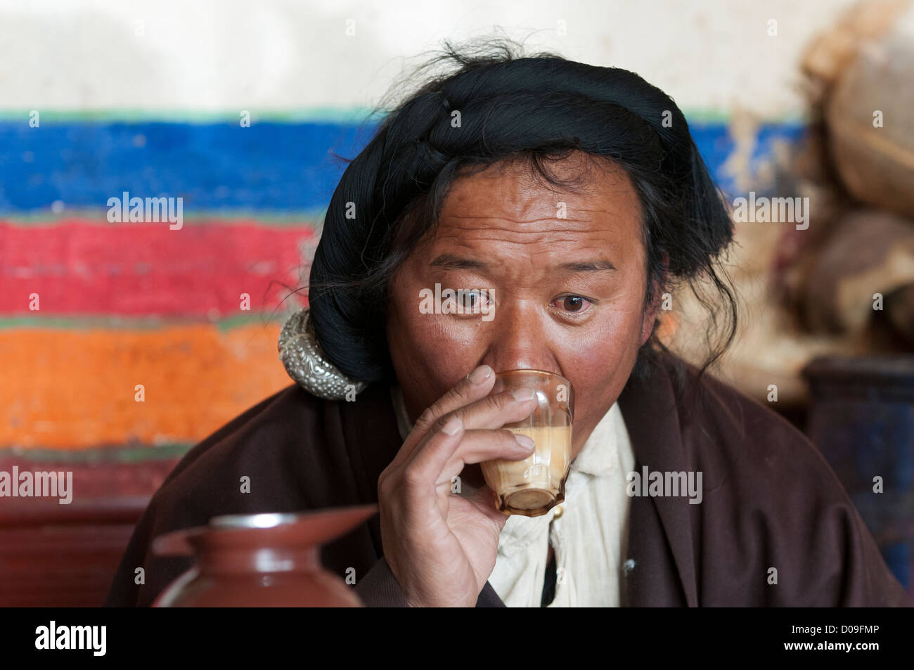Mit Silber sein Haar geflochten nippt tibetische Hirten Yak Buttertee im Straßencafé, Namtso, Tibet, China Stockfoto