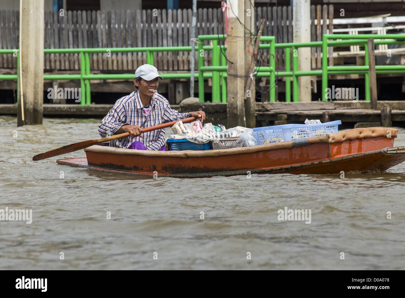 17. November 2012 - Paddel Bangkok, Thailand - ein Mann, der von seinem Boot, Tür zu Tür verkauft seine Kanu auf einem Khlong oder Kanal, im Abschnitt "Thonburi" von Bangkok. Bangkok war früher bekannt als das "Venedig des Ostens '' aufgrund der Anzahl der Wasserstraßen, die Kreuz und quer die Stadt gekreuzt. Nun die meisten der Wasserstraßen ausgefüllt aber Boote und Schiffe nach wie vor eine wichtige Rolle im täglichen Leben in Bangkok. Tausende von Menschen pendeln täglich auf dem Chao Phraya Express Boote und Schnellboote, die ply Khlong Saen Saeb oder Boote verwenden, um die Kanäle auf der Thonburi-Seite des Flusses zu erkunden. Boote sind uns Stockfoto