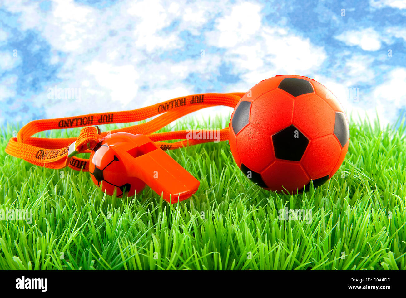 Orange Fußball und Querflöte auf Rasen gegen blauen Wolkenhimmel Stockfoto