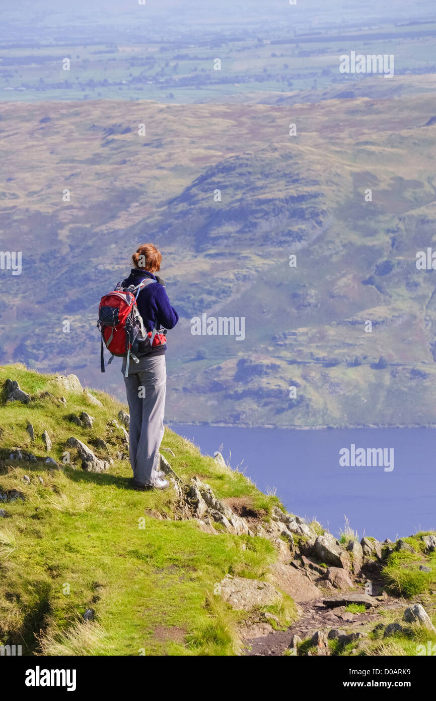 Eine weibliche Wanderer hält am langen Stil, nach Ansicht des Haweswater in der Ferne im Lake District zu nehmen. Stockfoto
