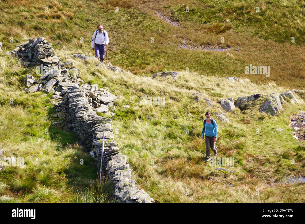 Zwei Wanderer zu Fuß in Richtung rauen Felsen im Lake District. Stockfoto