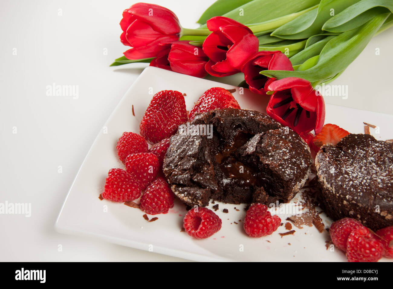 Lava-Schokoladenkuchen mit Beeren und Blumen Stockfoto