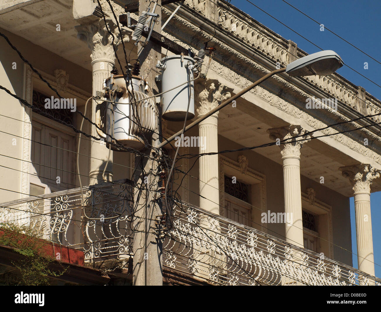 Hell erleuchtete Gewirr von Drähten und Kabeln mit Pflanzen Säulen und Geländer auf dem Balkon der alten kolonialen Gebäude in Moron Kuba Stockfoto