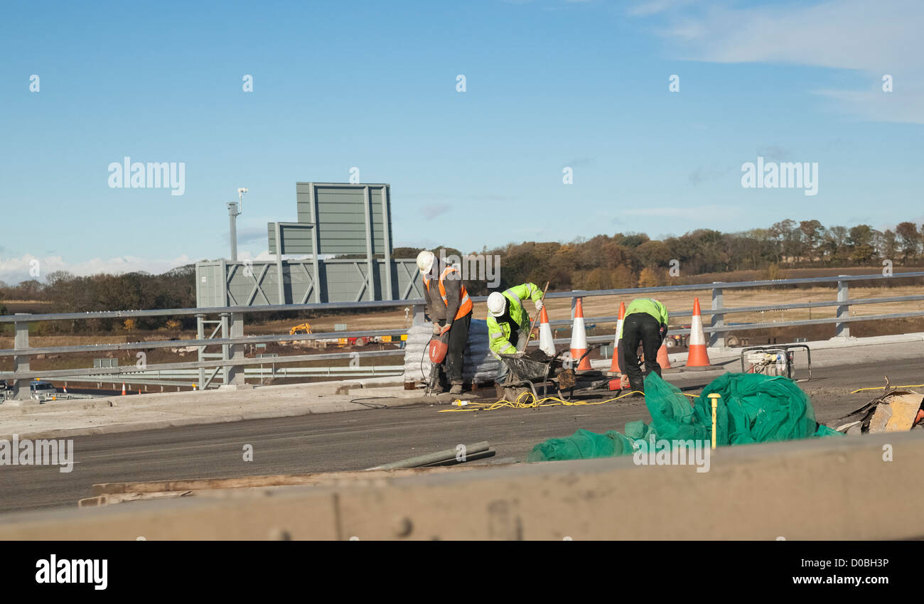 Männer bei der Arbeit auf der Autobahn an einem sonnigen Tag. Stockfoto