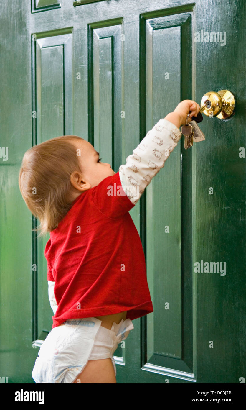 Achtzehn Monate alten Jungen versuchen, Tür mit Schlüssel entsperren Stockfoto