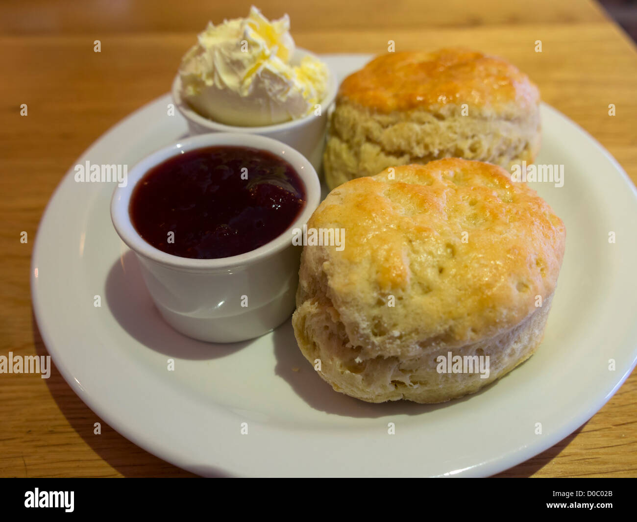 Cornish cream Tea. Hausgemachte Scones mit Clotted Cream und Erdbeermarmelade auf einem weißen Teller. Stockfoto