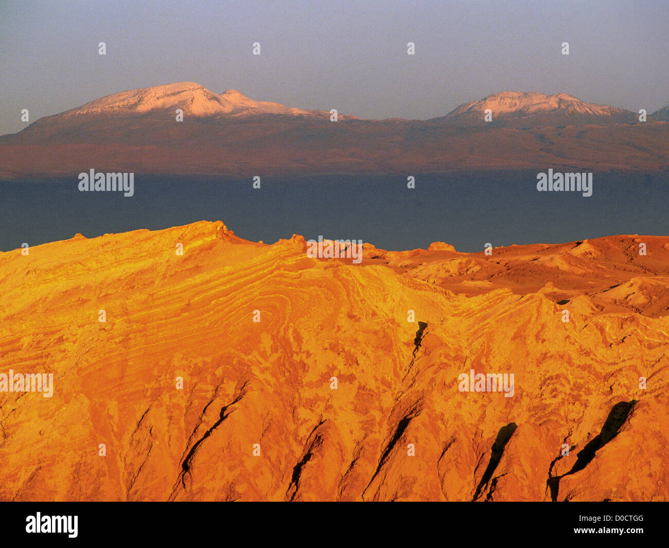 Das Licht der untergehenden Sonne beleuchtet die verdrehten Felsformationen der Chiles Valley of the Moon und die fernen Gipfel der Anden Stockfoto