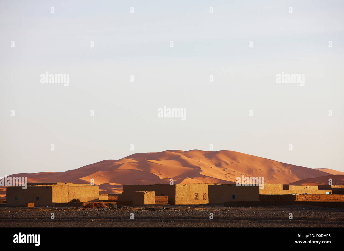 Irdener Gebäude im Vordergrund und massiven Dünen von Erg Chebbi in Hintergrund, innere Wüste Sahara, Marokko Stockfoto