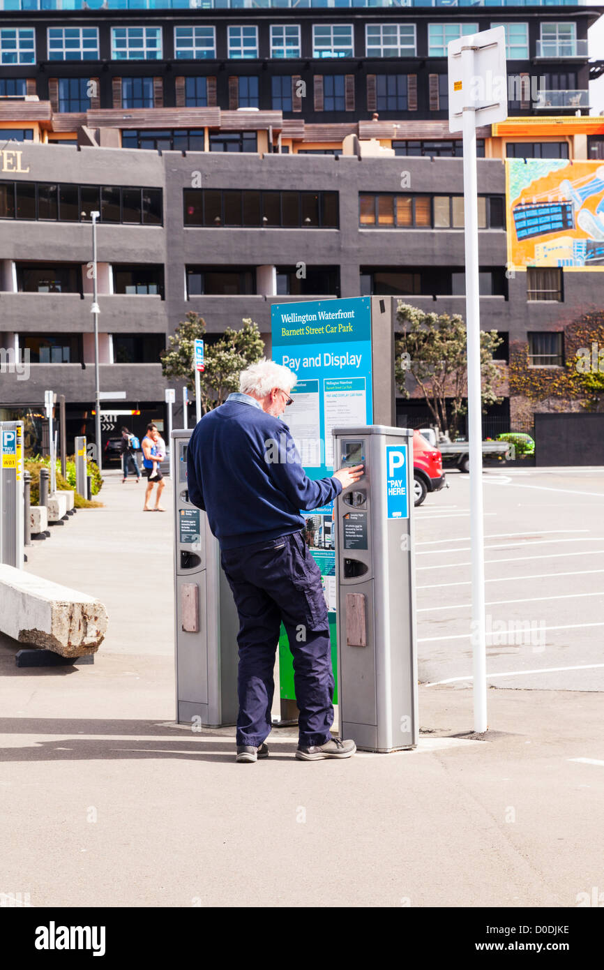 Ältere Mann mit Zahlen und Anzeige Parkuhr in Wellington New Zealand. Model Release für ältere Menschen zur Verfügung. Stockfoto