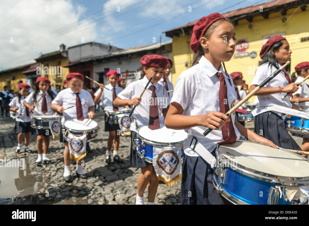 Guatemaltekische Unabhängigkeitstag Parade Schule Marching Band Antigua Guatemala // am Vormittag am Tag vor dem Tag der Unabhängigkeit Guatemalas (der am 15. September gefeiert wird) marschieren Hunderte Schulkinder aus Antigua und den umliegenden Dörfern in einer Parade von Schulgruppen in Antigua, einige in Kostümen und andere in Schuluniformen. Die Parade umfasst auch Schulmarschbands und Cheerleader. Die Prozession beginnt am Parque Central und schlängelt sich vorbei an der leuchtend gelben Kirche La Merced in das Stadion der Stadt. Stockfoto