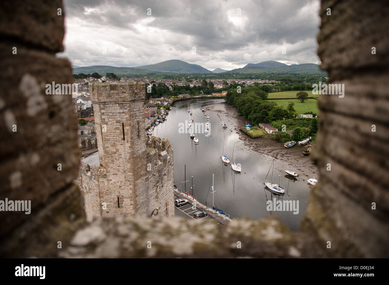 CAERNARFON, Wales – Blick auf den Fluss und die Boote von einem Turm auf Caernarfon Castle im Nordwesten von Wales. Ursprünglich stand an der Stelle eine Burg aus dem späten 11. Jahrhundert, aber im späten 13. Jahrhundert ließ König Eduard I. ein neues Gebäude in Auftrag geben, das bis heute besteht. Es hat markante Türme und ist eines der am besten erhaltenen Burgen der Reihe, die Edward I. in Auftrag gab. Stockfoto