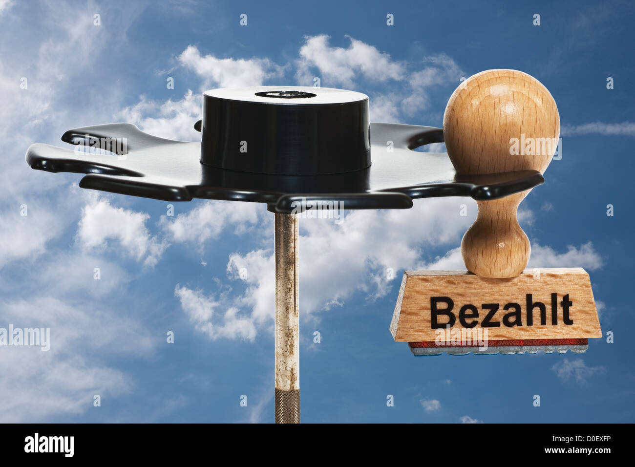 Stempel mit deutscher Inschrift Bezahlt (bezahlte) hängt in einem Stempel Rack, Hintergrund Himmel Stockfoto