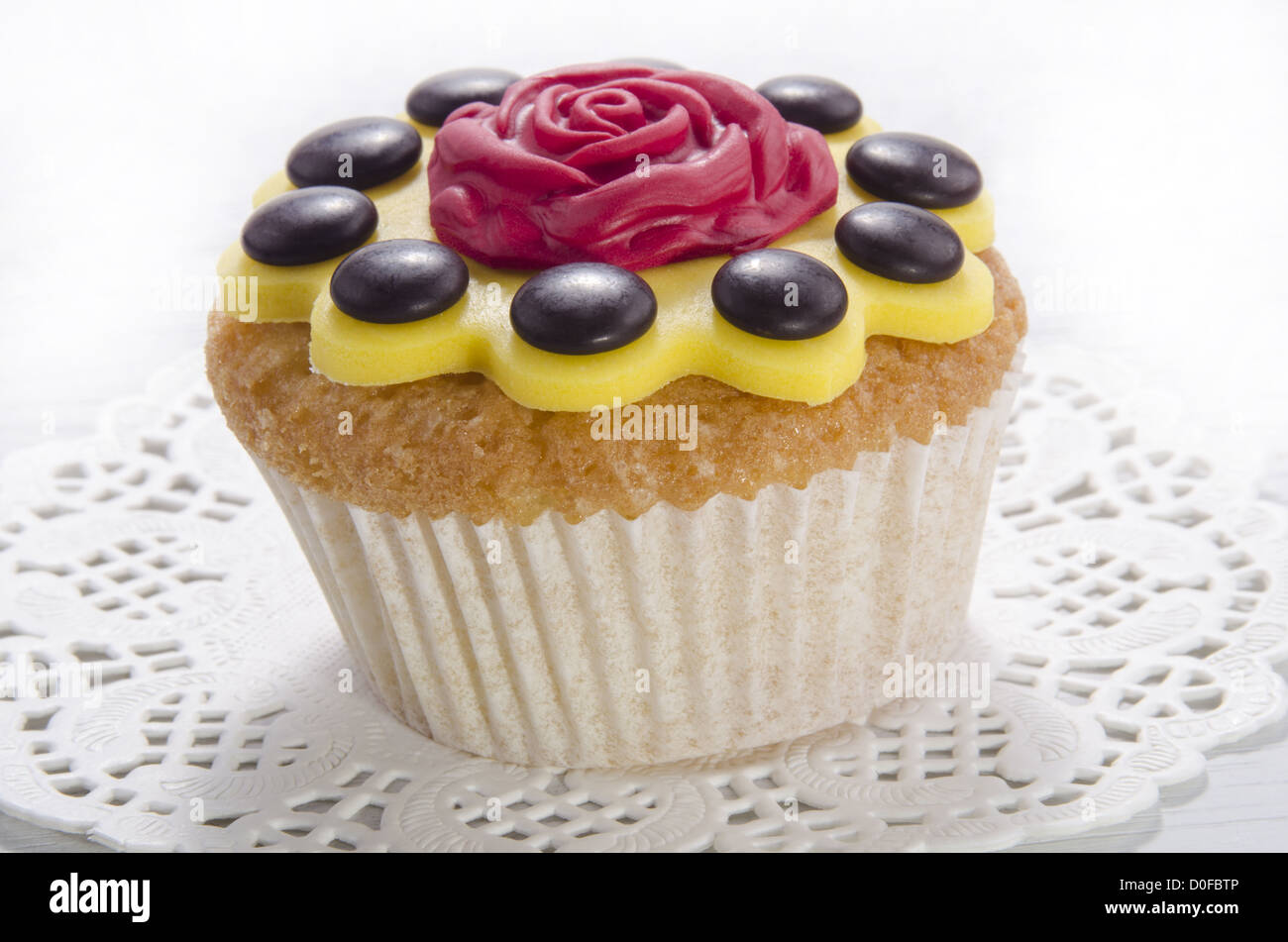 Cupcake mit gelber Zuckerguss und rote rose Stockfoto