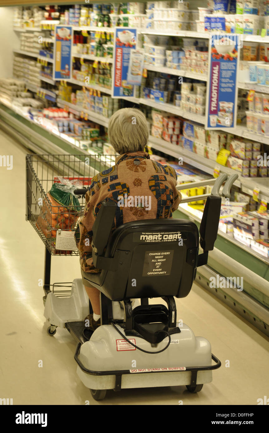 Eine Frau auf einem Mobilitätsroller, die in einem Supermarkt in Ontario, Kanada, einkauft. Innenansicht. Gang. Regale. Öffnen Stockfoto