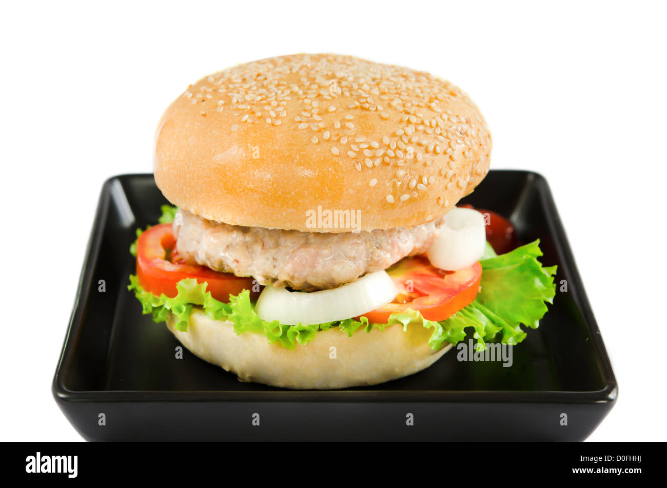 ein Burger serviert mit Schweinefleisch und frischem Gemüse auf schwarzem Teller Stockfoto