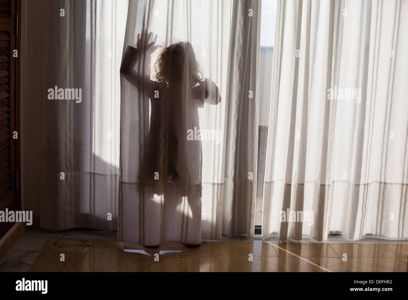 anonyme Mädchen Silhouette winken hinter Gardinen Stockfoto