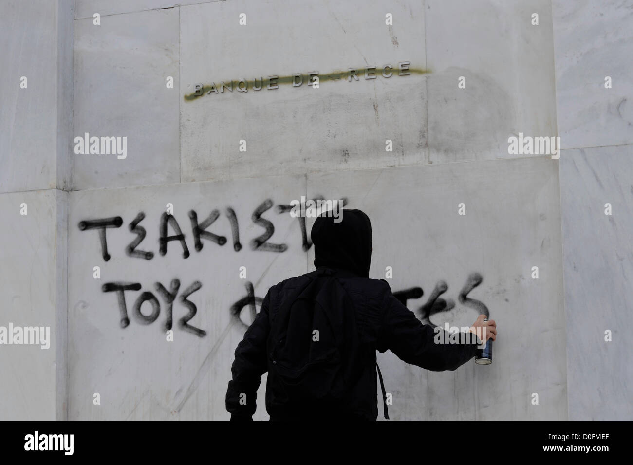 Ein maskierter Demonstrant besprüht die Worte "zerkleinert die Faschisten" an der Wand von der Banque de Grece während einer antifaschistischen Protest in Athen am 24.11.2012 März. Mindestens 1.000 Personen nahmen an der Demonstration, die vom antifaschistischen Gruppen organisiert wurde. Stockfoto