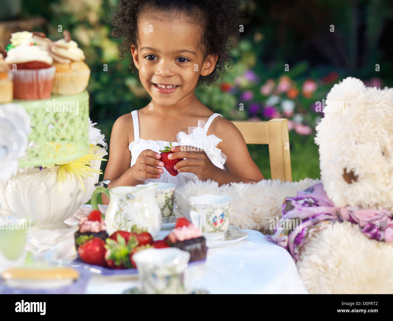Führerschein erhältlich unter MaximImages.com - Happy lächelndes Mädchen bei einer Sommerparty im Freien. Ich trinke Tee mit Cupcakes. Stockfoto