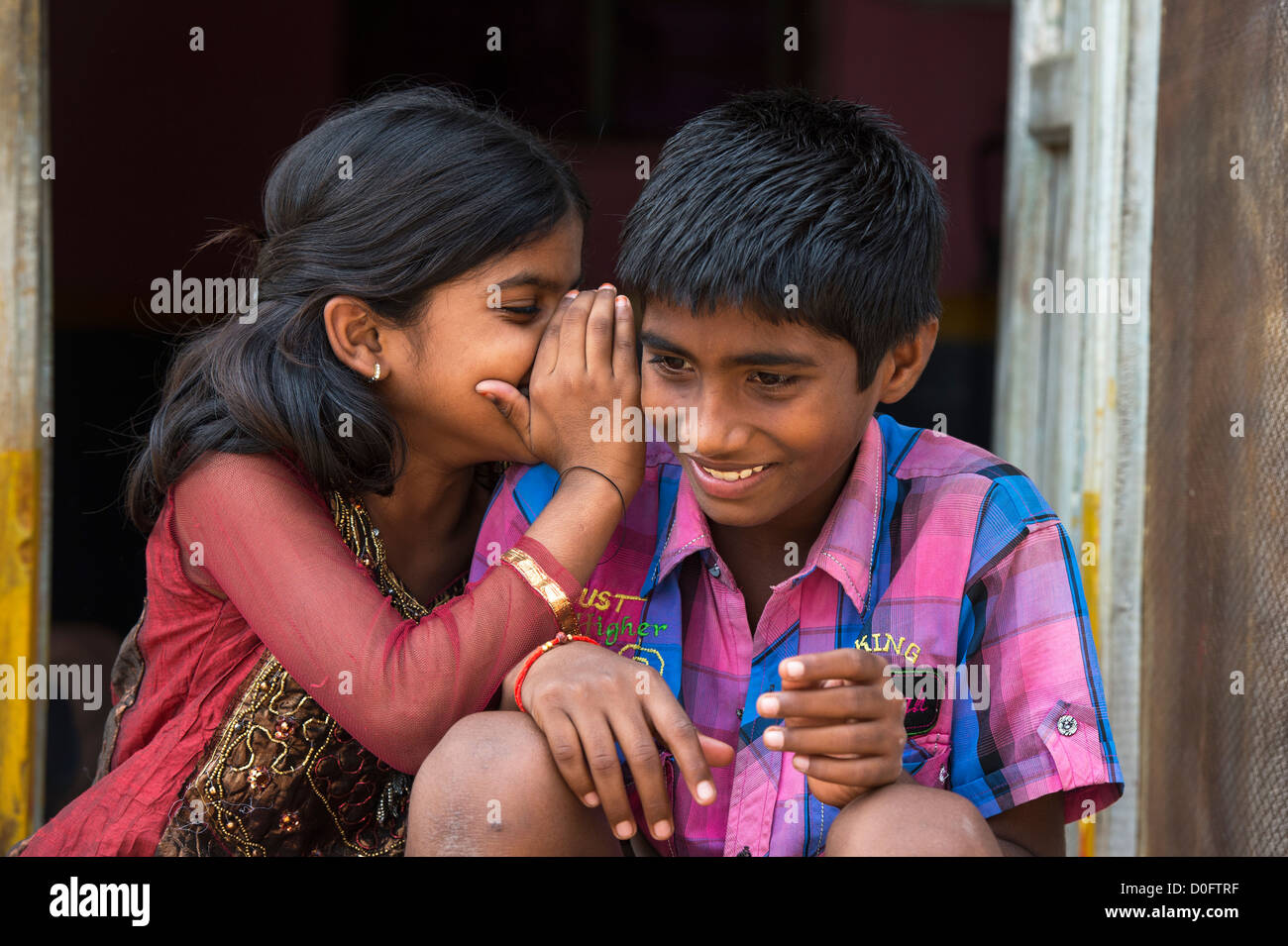 Junge Inderin Flüstern zu einem jungen außerhalb ihrer ländlichen indische Viilage nach Hause. Andhra Pradesh, Indien Stockfoto
