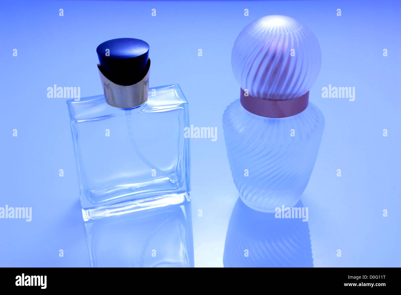 Zwei Parfümflaschen isoliert mit Reflexion in blaue Tönung Stockfoto