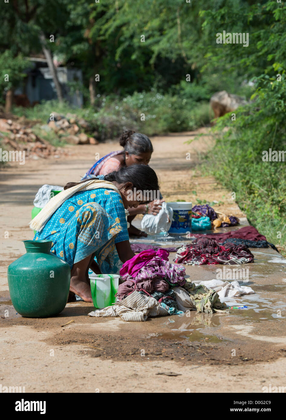 Indische Frauen, die Wäsche von Hand auf einem ländlichen Dorfstraße. Andhra Pradesh, Indien Stockfoto