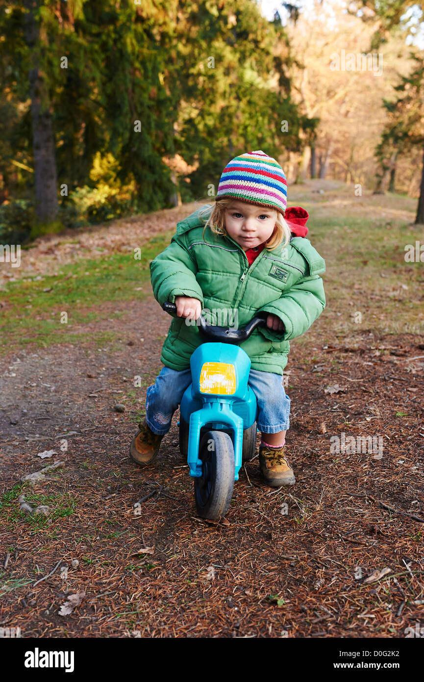 Einjähriges Mädchen reiten Kleinkind Kunststoff Trike (Dreirad) im Herbst  park Stockfotografie