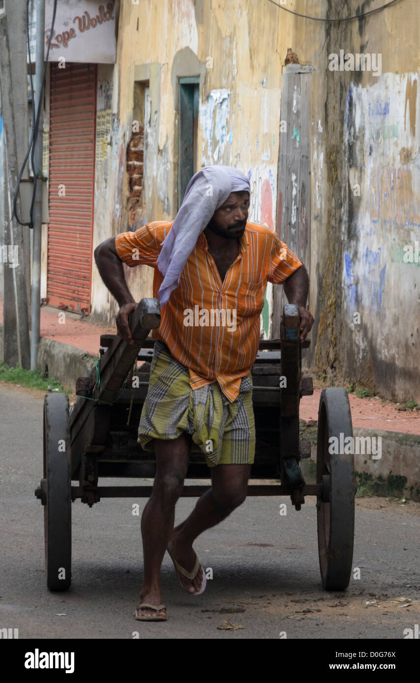 Ein Arbeiter zieht einen Karren in den Straßen von Cochin, Kerala Indien Stockfoto