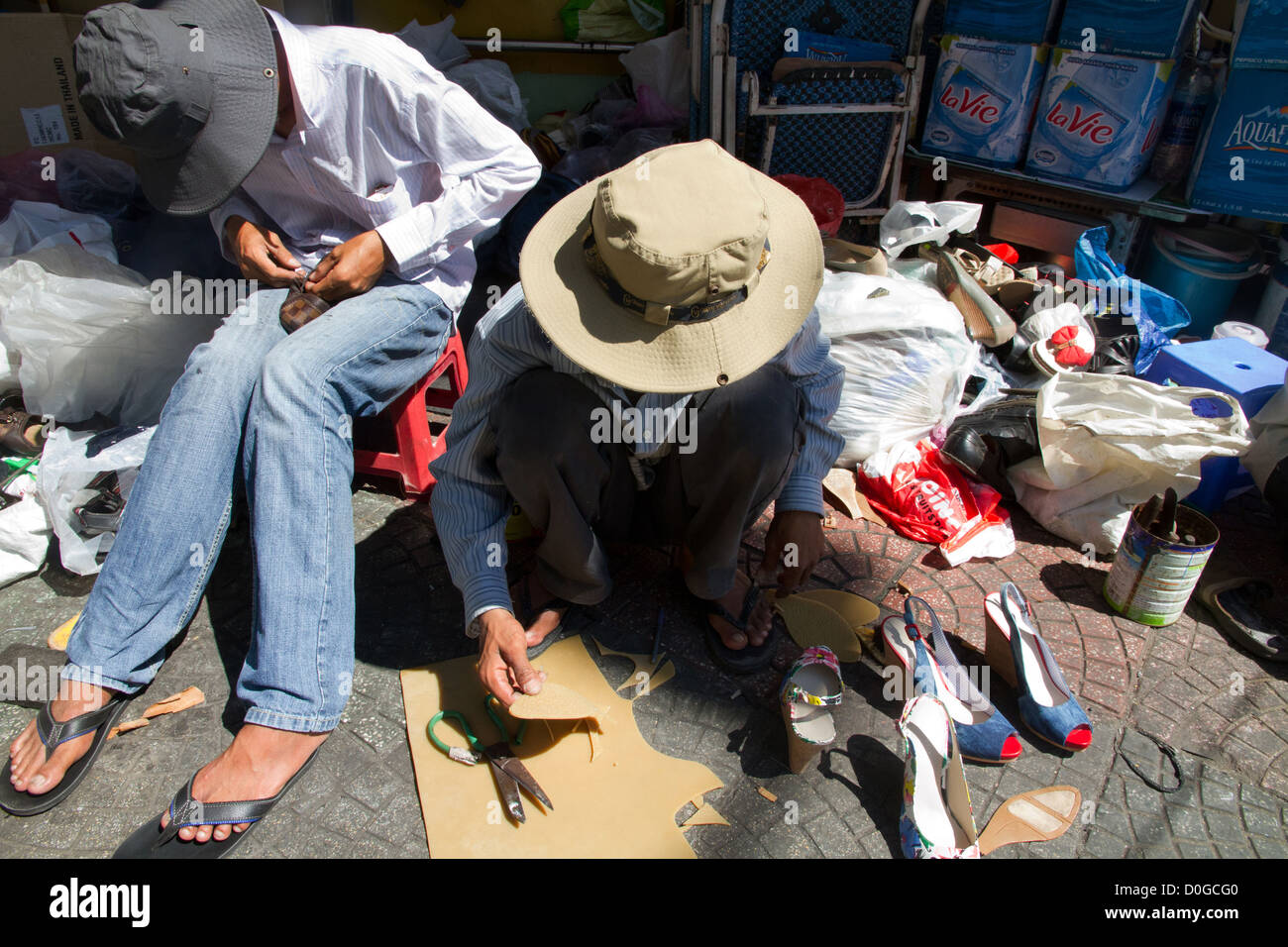 Schuh-Werkstätten arbeiten in den Straßen von Ho Chi Minh City, Vietnam. Stockfoto