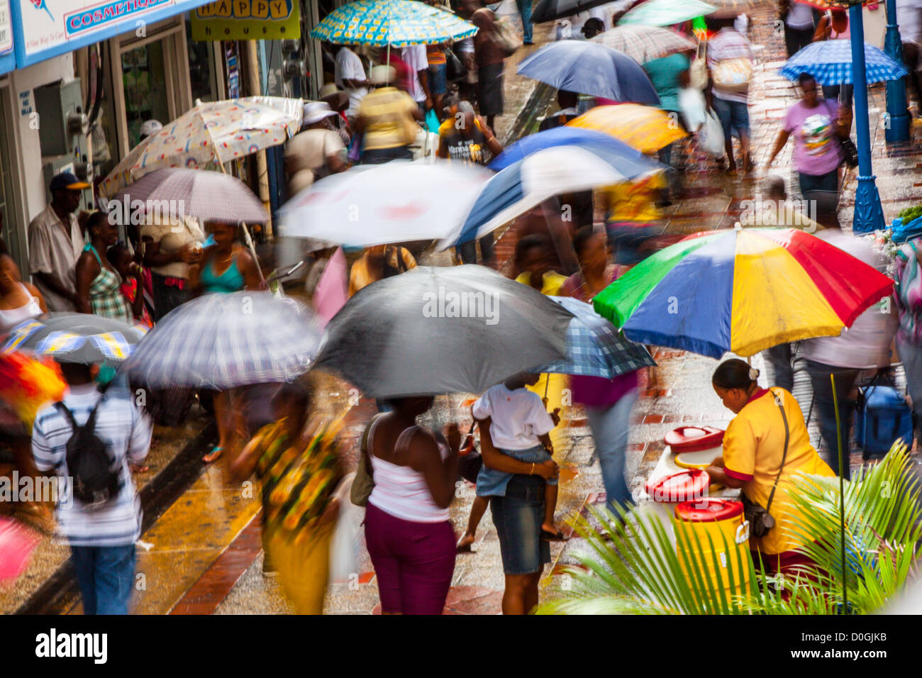 Belebte Straße Einkaufsmeile in Bridgetown an einem regnerischen Tag mit Menschen halten Sonnenschirme, Barbados, West Indies Stockfoto