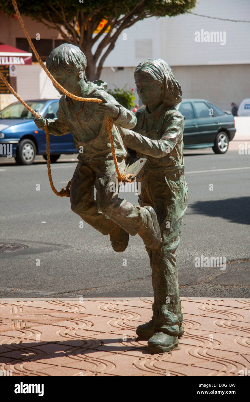 Skulptur von Kindern spielen auf einer Schaukel "Cruce de Arinaga", [Gran Canaria]. Stockfoto