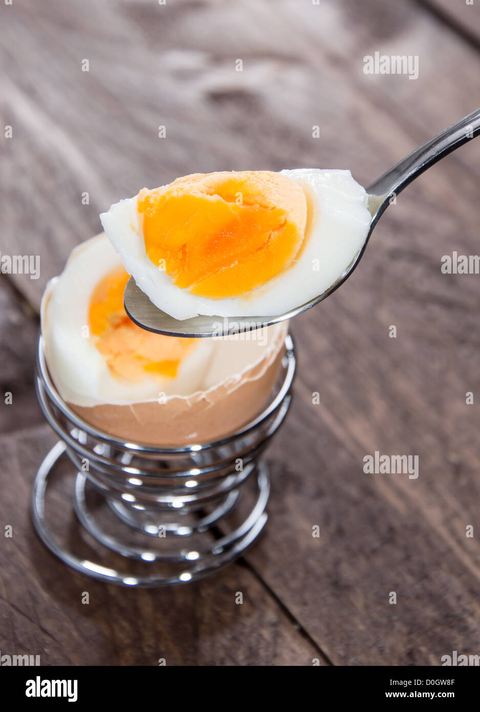 Löffel mit Frühstück Ei auf hölzernen Hintergrund Stockfoto