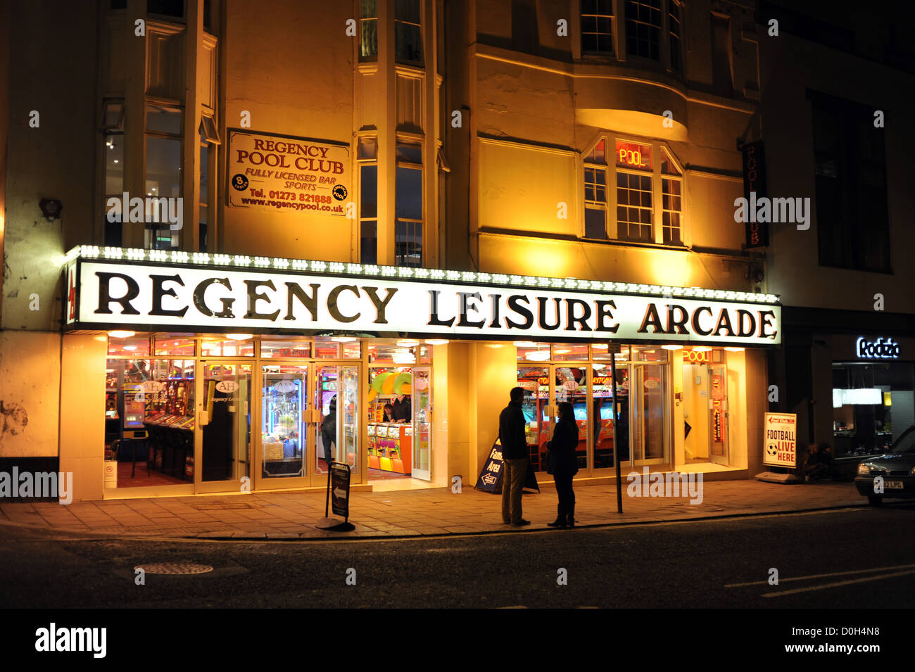 Die Regency-Freizeit mit zwei Personen draußen am Bürgersteig in der Nacht in West Street Brighton UK Stockfoto