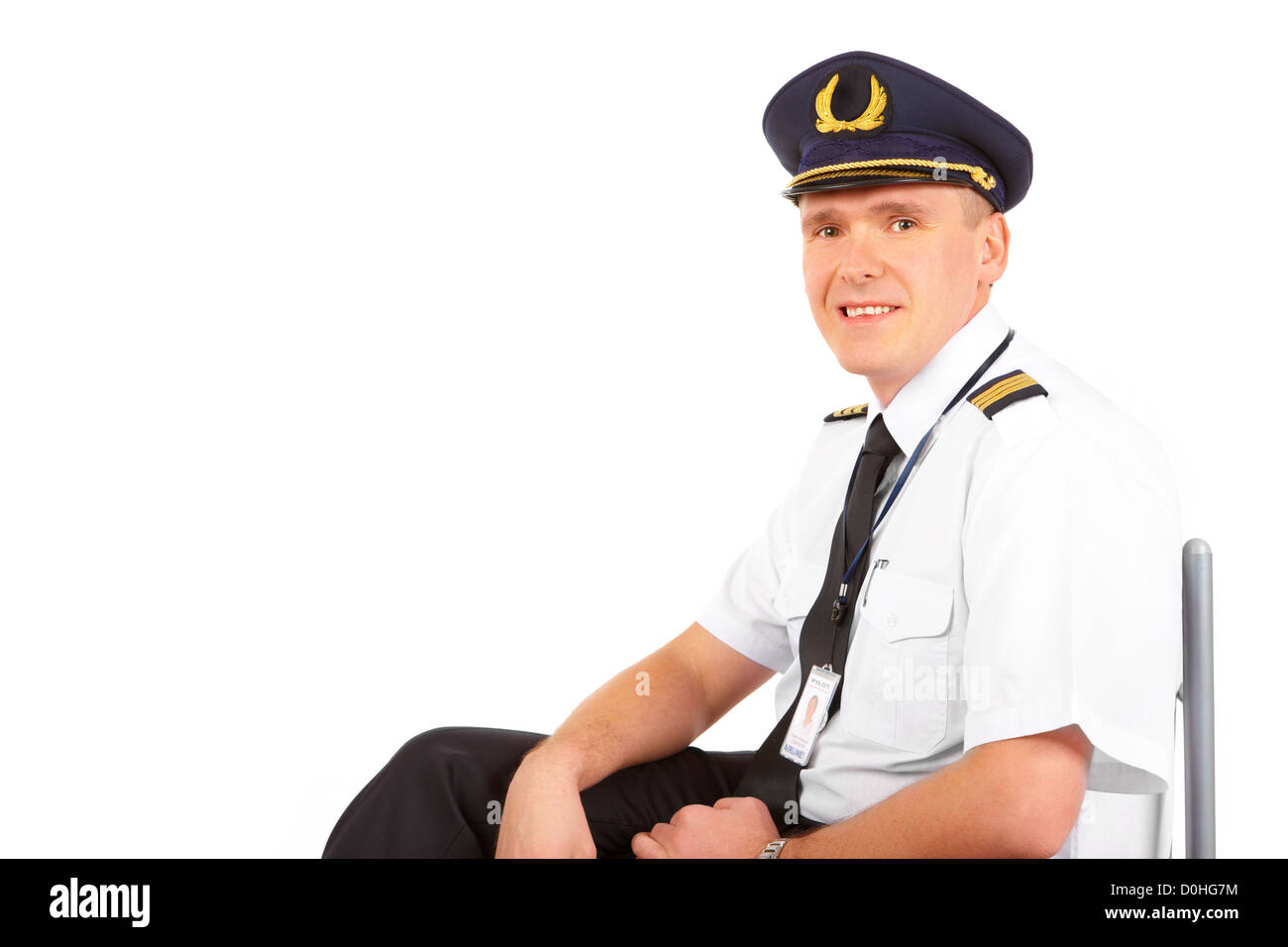 Fröhlichen Piloten tragen Uniform mit Epauletten und Hut mit goldenen Flügeln, sitzend, isoliert