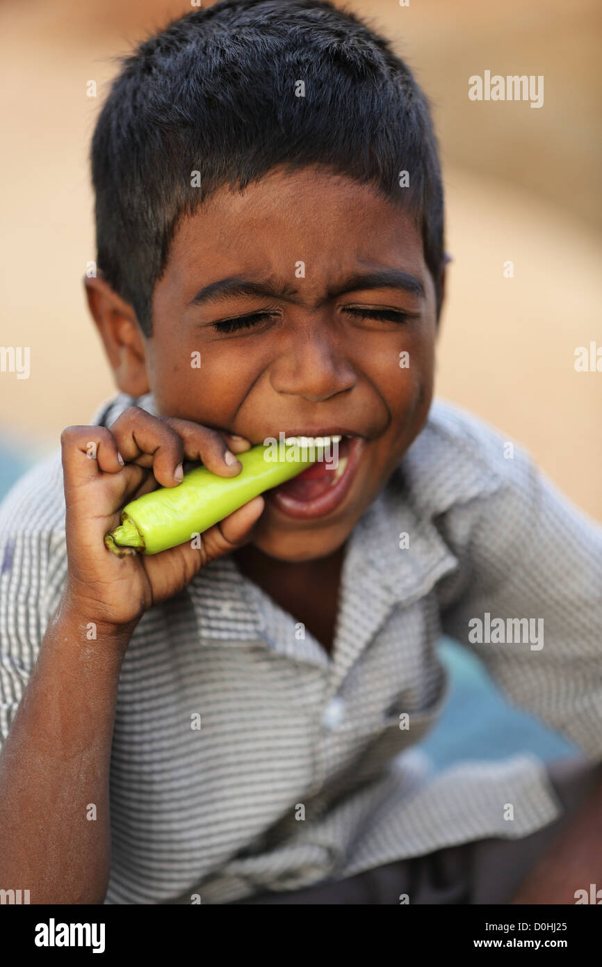 Indianerjunge reagieren beim beißen in eine grüne Chili Andhra Pradesh in Indien Stockfoto